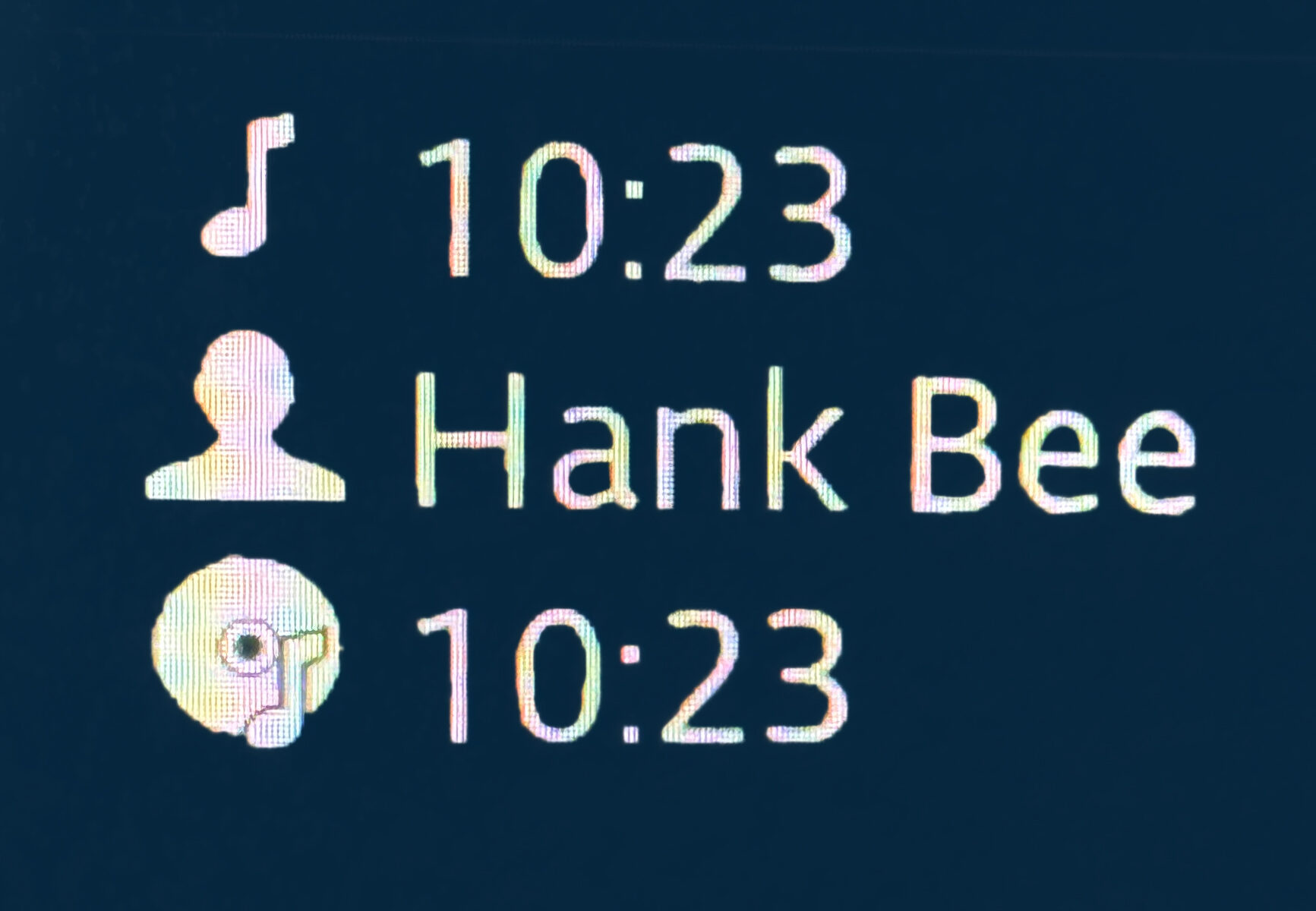 Car stereo music display showing band name and song name - "Hank Bee, 10:23"